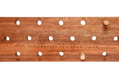 A wooden pegboard with a warm medium-brown wood grain finish, featuring multiple circular peg holes and two wooden pegs, shown against a plain white background.