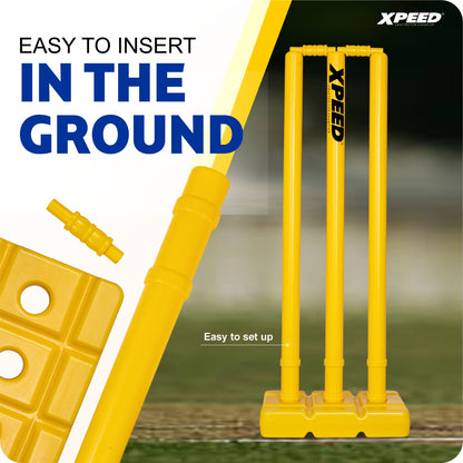 Yellow Xpeed brand cricket stumps and matching plastic accessories shown with marketing text on a split white and blurred outdoor background.