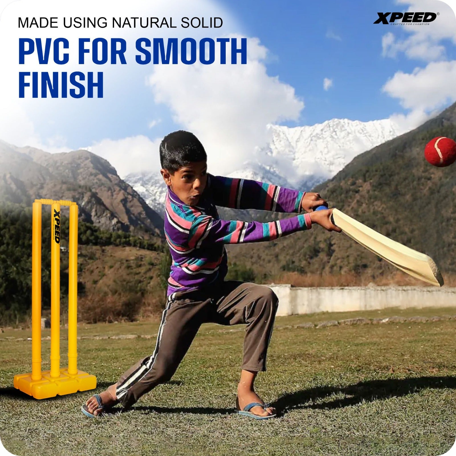 A boy in a colorful striped shirt swings a cricket bat outdoors, hitting a red cricket ball near yellow stumps. Snow-capped mountains and a blue sky are in the background, with text reading 'MADE USING NATURAL SOLID PVC FOR SMOOTH FINISH' and the Xpeed logo in the top right.